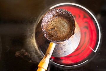 invigorating coffee in an old Turkish pot on a hot stove on a bright spring morning is prepared and infused