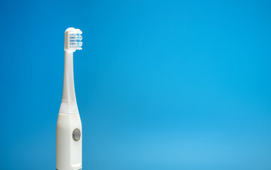 Electric ultrasonic toothbrush on blue background.