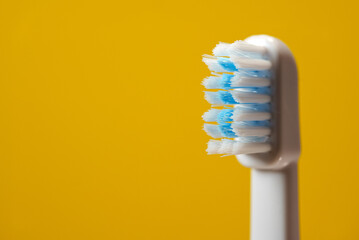Electric ultrasonic toothbrush bristles on yellow background.