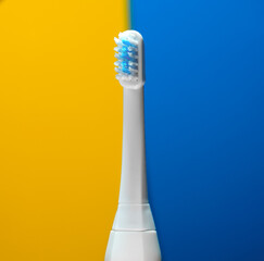 Fototapeta na wymiar Electric ultrasonic toothbrush on yellow blue background.