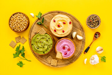 Flatlay of different types of colorful hummus in bowls. Vegan food background