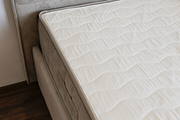 Obraz na płótnie Canvas White orthopedic mattress top side surface pattern on unmade bed in the bedroom. Hypoallergenic foam mattress for proper spinal alignment and pressure point relief. Background, copy space, close up.