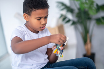 A dark-skinned boy playing and looking involved