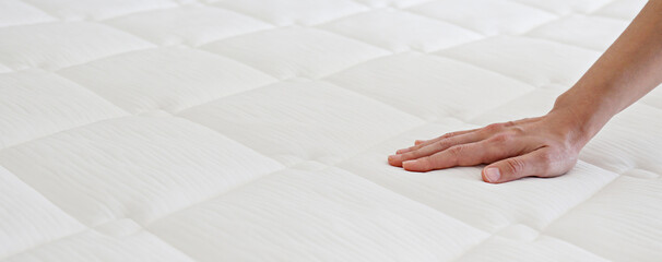Cropped shot of young woman's hand testing white orthopedic matress on firmness. Female pressing...