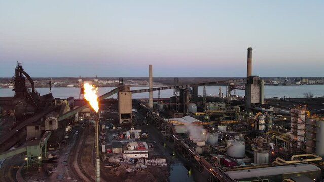 Zug Island Steel Factory, Steel mill in Detroit, Michigan aerial panning shot with burning chimney at twilight.
