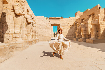 A happy tourist girl in a dress is interested in Egyptology and archaeology and gets a travel...