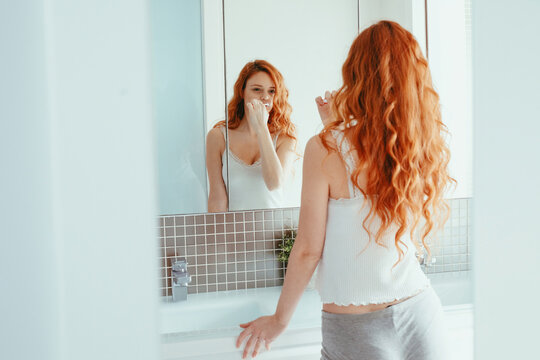 Woman brushing teeth in bathroom