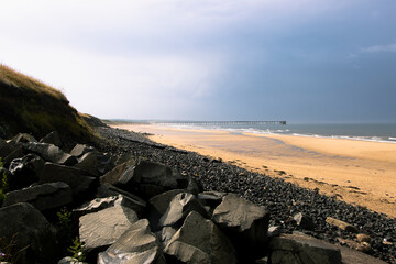 Black rocks and beach sand on stormy day at Hartlepool Headland, UK