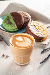 A glass of cappuccino or latte with foam and an artistic pattern. Coffee and cookies on the table for breakfast