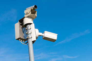 Surveillance cameras on a metal bar. Against the background of the blue sky.