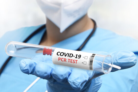 NHS Technician Holding COVID-19 Swab Collection Kit Wearing White PPE Protective Suit And Mask