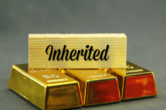 three gold nuggets and a wooden board with the word inherited