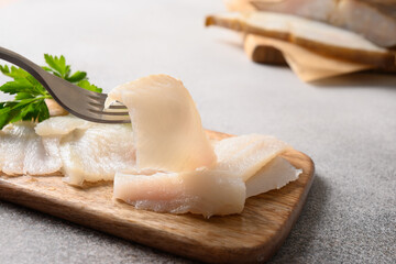 Smoked halibut slices on gray background. Man eating delicacy fish. Close up. Rich of healthy omega...
