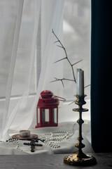 Household items created a harmonious, festive composition.Pearls, candle, turtle figurine.Cross, lamp, shadow drawing from the window.Bijouterie, a cross on a sunny windowsill.