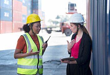 Female docker is discussing with a customer at cargo warehouse. 