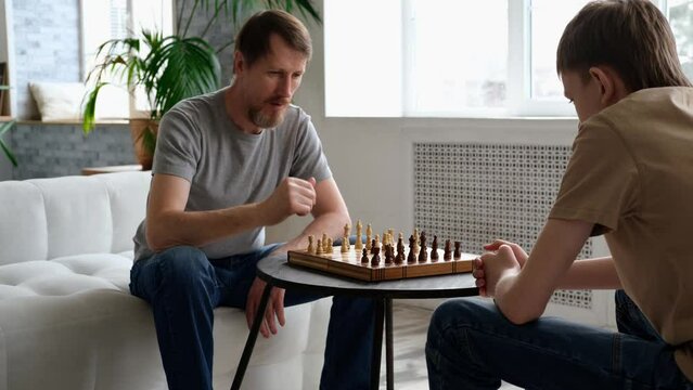 Father and son playing chess at home. Family leisure together