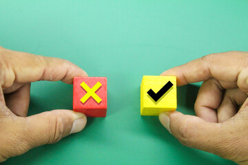 hands holding colored cubes with wrong and correct icons. the concept of selection or segregation