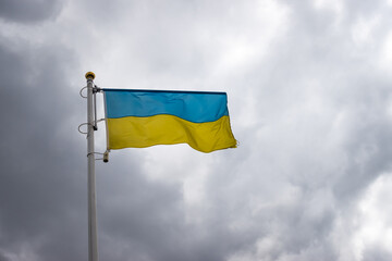 Ukrainian banner wave on the background of cloudy, dramatic sky. Picture taken in the day, sky full of clouds.