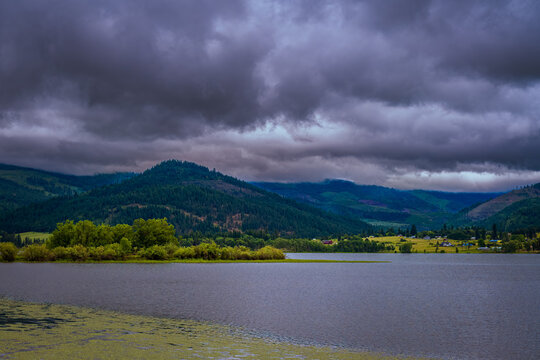 COUER D'ALENE RIVER WITH A MOUNTAIN RIDGE AND DARK CLOUDS