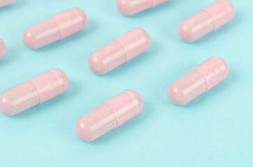 Obraz na płótnie Canvas Pink capsule pills on blue background.