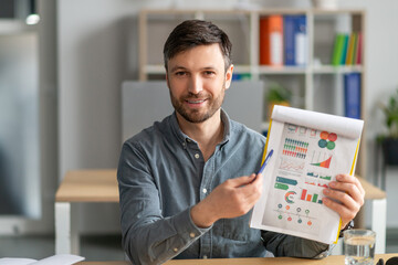 Online meeting concept. Mature businessman having video call, showing diagrams to laptop camera, sitting in office