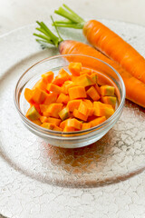 Sliced carrot in a glass cup on a silver tray.