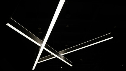 Low angle shot of glowing intersecting linear lights in the darkness - obrazy, fototapety, plakaty