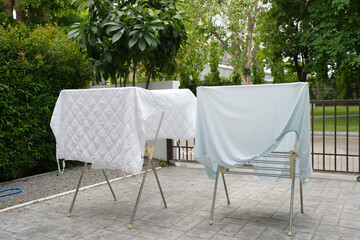 Dry white bed sheets hanging on hanger outdoor.
