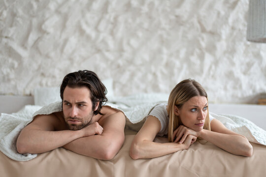 Sexual problems, relationship crisis. Stressed young couple lying in bed, overwhelmed with family difficulties at home