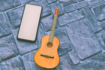 Phone with space for text, acoustic guitar on a cobbled grey blue background