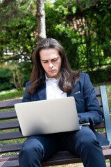 young man sitting on the bench consulting a laptop computer