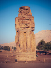 Vertical shot of the massive stone statue - Mennon Colossus against the blue sky in Egypt
