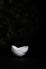 Vertical shot of a marble plate inside another one on a black textured background with copy space