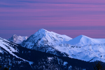 Naklejka na ściany i meble Sunset on snow covered mountains, with red and pink clouds