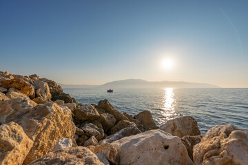 Sunset at rocky stone beach in Albania. Adriatic sea, peninsula Karaburun on horizon - obrazy, fototapety, plakaty