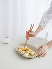 Adult female hands taking piece of Dan Bing (Taiwanese egg crepe) with wooden chopsticks