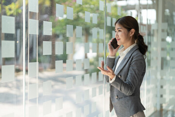Smiling business asian woman in talking consultant on mobile phone at modern office
