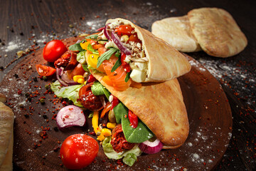 Whole pita with salmon and vegetables on wooden background. Front view