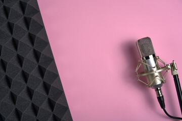 Fototapeta na wymiar Microphone on pink background with copy space and acoustic foam panel