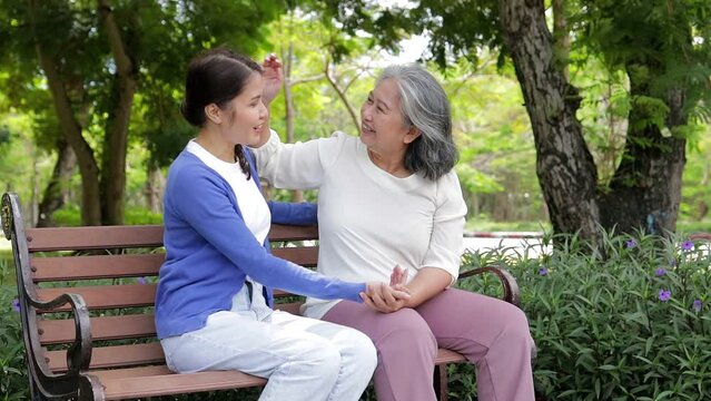 daughter with elderly mother Sitting in the park in the morning They smile happily. Family concept. Health care for the elderly in retirement age. Nursing care for the elderly.