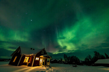 Northern Lights in the arctic winter with snow and chalets © Filippo
