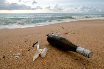Obraz premium Plastic Pollution and Glass Bottle on Sandy Beach Promoting Marine Conservation Awareness