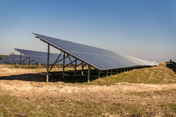 Many solar panels in northern Poland, providing energy to surrounding houses. Solar energy farm made of many panels in rows. Clear sky with no clouds and sunny weather.