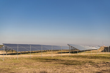 Many solar panels in northern Poland, providing energy to surrounding houses. Solar energy farm made of many panels in rows. Clear sky with no clouds and sunny weather.