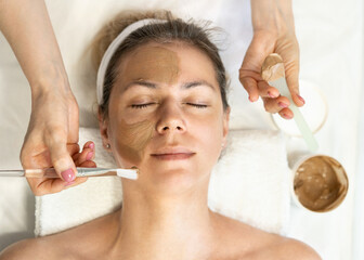 he face of a white woman undergoing cosmetic procedures. Brown clay face mask. Facial care....