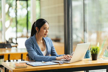 Portrait of Asian young female working on laptop and financial report at office.