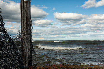 Stormy sea and an old fence on the shore. Atlantic Ocean. USA. Maine.