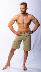 Fototapeta na wymiar muscular man in shorts posing, shows, straining muscles. gray background