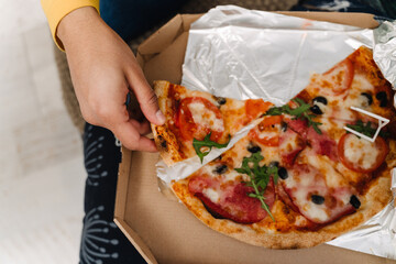 Teenage boy eating pizza while sitting on couch at home