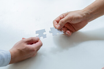 two man hands holding jigsaw puzzle teamwork concept